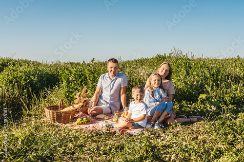 Happy family have a rest together in a picnic outdoors. Blue pink clothes, casual. Beautiful mother, father and children.