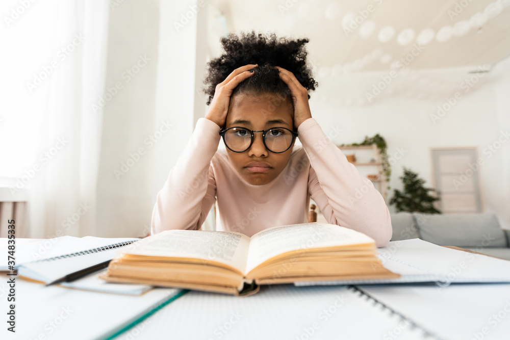 Frustrated Black Girl Looking At Camera Sitting At Book Indoors Frustrated Black Girl Looking At Camera Sitting At Book Indoors