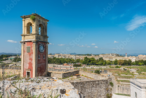 Clock tower at the old fortress at Corfu city with the esplanade and the old town on the background. Greece 2020.