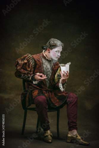 Eating wok food. Young man as Johann Bach isolated on dark green background. Retro style, comparison of eras concept. Beautiful male model like historical character, great music composer, old