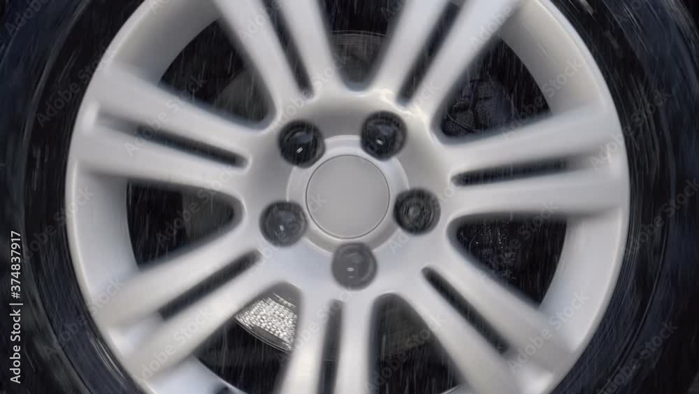 Added shaking from moving the car! A car wheel with a shiny silver rim rides in the rain drops and strong shaking on bad road. Closeup. Slow mo, slo mo, slow motion, high speed camera Added shaking from moving the car! A car wheel with a shiny silver rim rides in the rain drops and strong shaking on bad road. Closeup. Slow mo, slo mo, slow motion, high speed camera