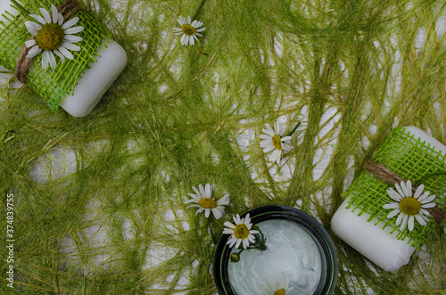 Cream, handmade soap, chamomile flowers on a green sisal background. Organic cosmetics based on chamomile extract. photo