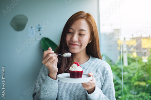 Canvas Print A beautiful asian woman enjoyed eating red velvet cup cake