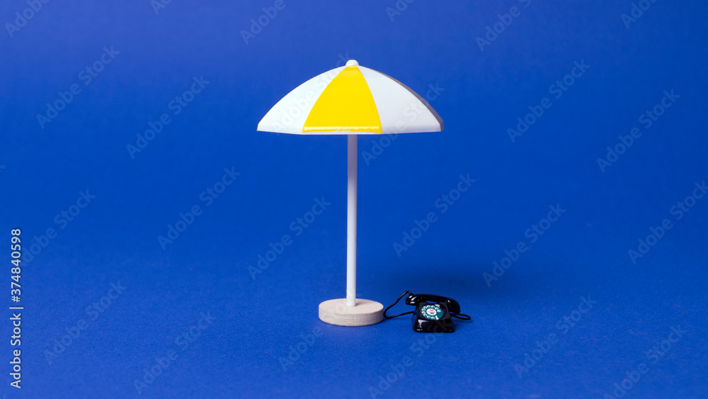 Fototapeta premium phone and multicolored beach umbrella on blue background