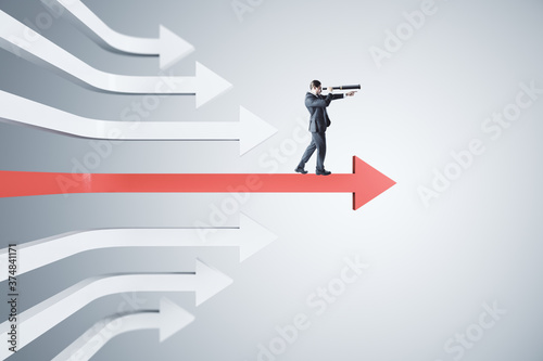 Businessman with telescope standing on red arrow