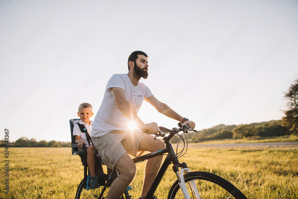 Father and his son cycling together outdoors Father and his son cycling together outdoors