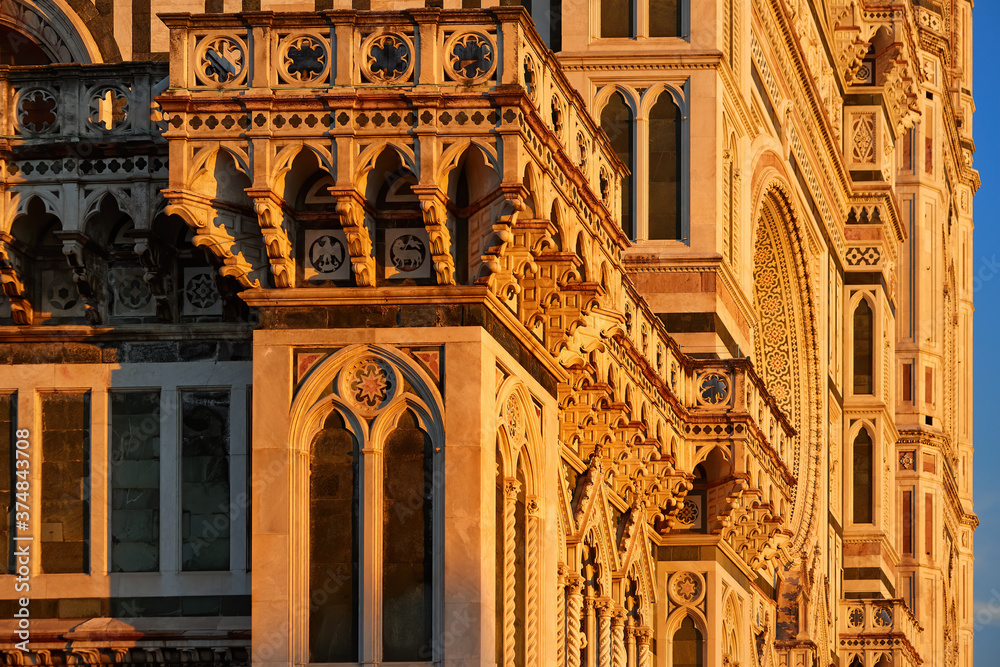 Cathedral of Saint Mary of the Flower in Florence. Tourist hotspot in Tuscany. Detailed view of a marble gothic ornaments, illuminated by red light of setting sun. Unesco site, Florence, Italy.