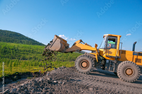 Front loader bucket unloads rock into a dump