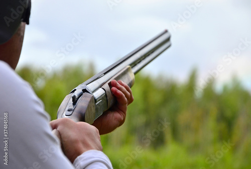 A shooter, hunter shoots a shotgun, a rifle at the plates against the background of a green forest