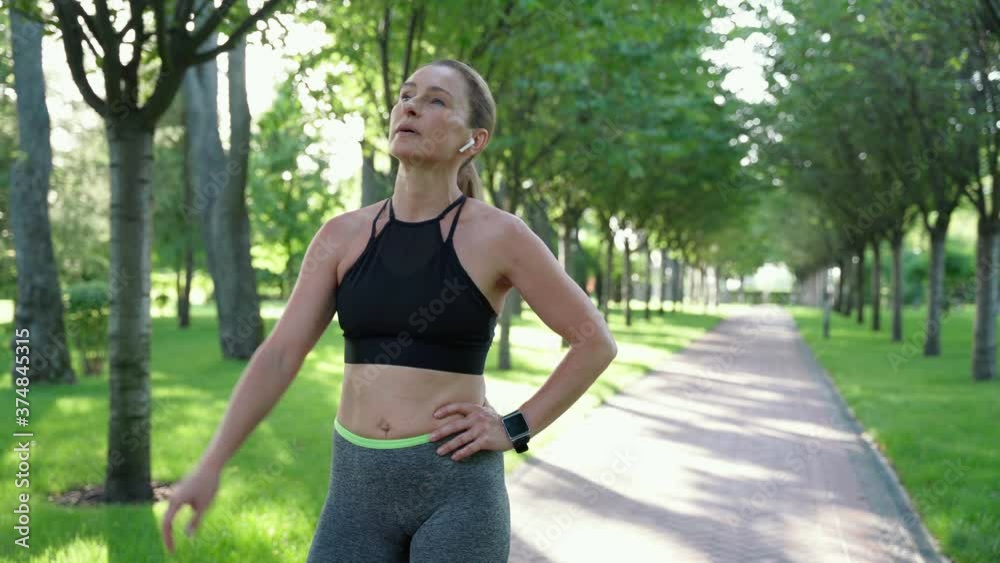 Exhausted athlete woman, female runner in sportswear breathing deep, resting after active morning workout in city park Exhausted athlete woman, female runner in sportswear breathing deep, resting after active morning workout in city park