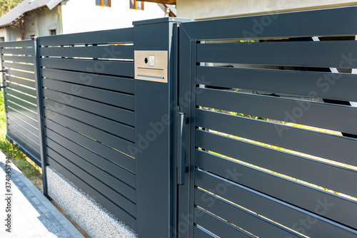 фотографія A modern videophone with a letterbox and a wireless card reader, mounted in panel fence in anthracite color, visible wicket