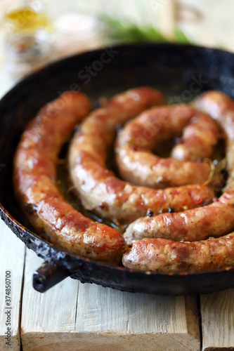Selective focus. Fried homemade sausages in a frying pan on a wooden table. Rustic style.