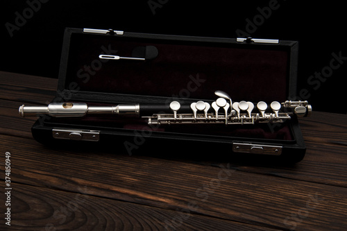 Musical instrument, flute with a case on a wooden surface on a black background