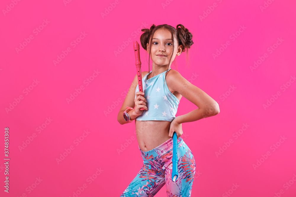Obraz premium young musician girl with pink pipe in her hand. flute folk music performance. isolated on pink background. copy space.