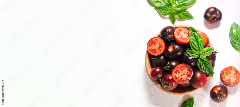 Fresh ripe tomatoes with basil leaves in the wooden bowl on white background top view. Long banner format. Fresh ripe tomatoes with basil leaves in the wooden bowl on white background top view. Long banner format.