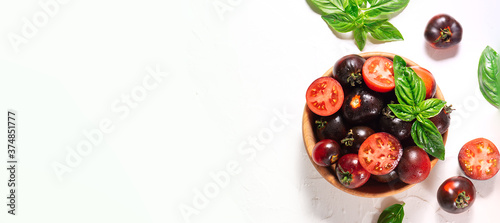 Fototapeta Naklejka Na Ścianę i Meble -  Fresh ripe tomatoes with basil leaves in the wooden bowl on white background top view. Long banner format.