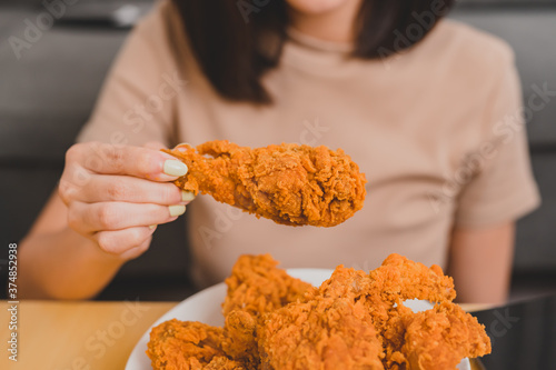 Eating fried chicken when takeout and delivery. Fast food takeaway back home.  Asian woman lifestyle in living room. Social distancing and new normal. photo