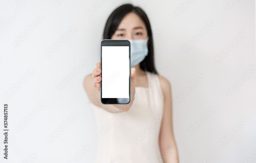 Asian woman showing mobile smart phone with blank white screen, and wearing medical face mask 