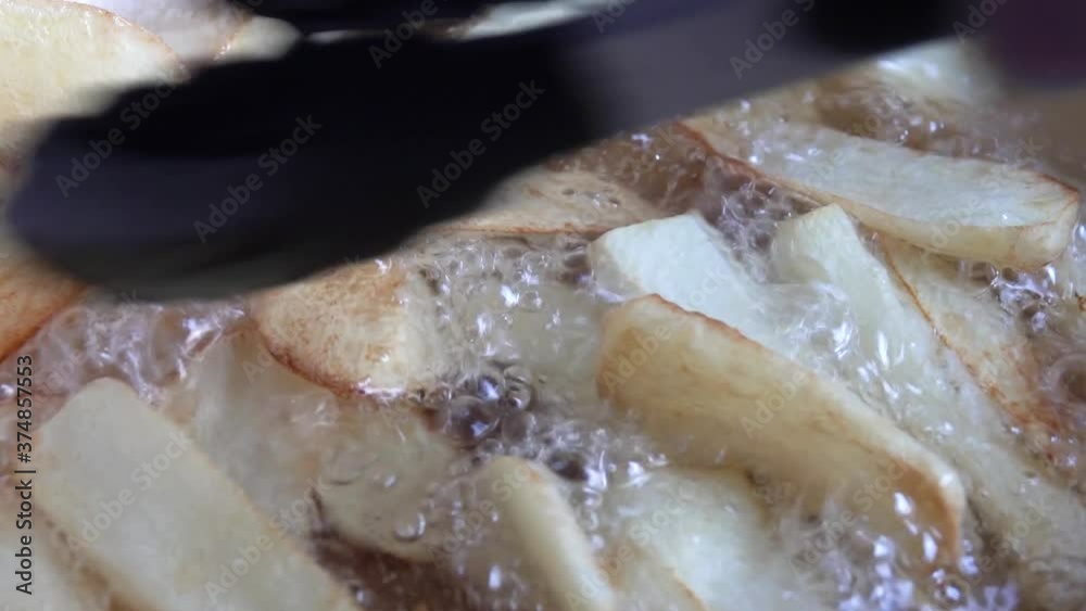 Close up of potatoes frying on hot boiling oil. Home made french fries fried in oil. Close up of potatoes frying on hot boiling oil. Home made french fries fried in oil.