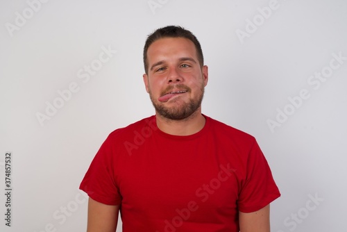 Wallpaper Mural Young caucasian man wearing red t-shirt over white background showing grimace face crossing her eyes and showing tongue . Being funny and crazy Torontodigital.ca
