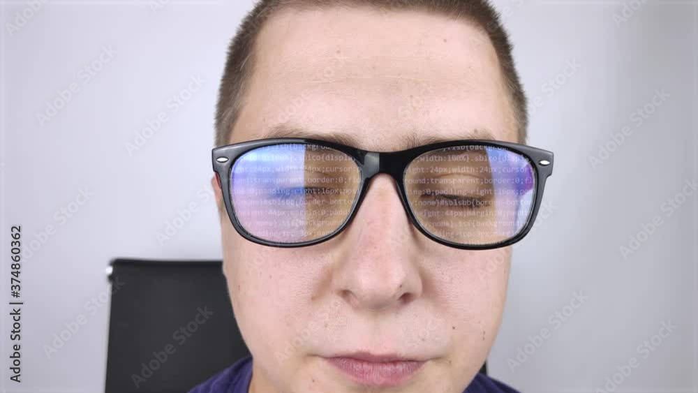 The programmer's glasses reflect moving lines of code. Programming, development of applications, websites and more. Software development concept The programmer's glasses reflect moving lines of code. Programming, development of applications, websites and more. Software development concept