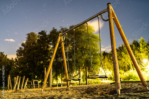 Metalowe huśtawki na drewnianej konstrukcji na tle gwieździstego nocnego nieba