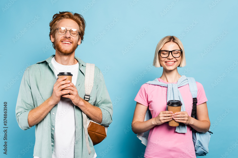 Fototapeta premium young students in glasses with closed eyes holding paper cups on blue