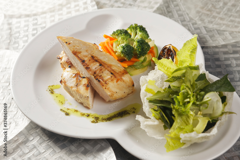 Roasted chicken breast served with a lettuce salad garnished with broccoli, carrot, pumpkin, and lemon juice. Roasted chicken breast served with a lettuce salad garnished with broccoli, carrot, pumpkin, and lemon juice.