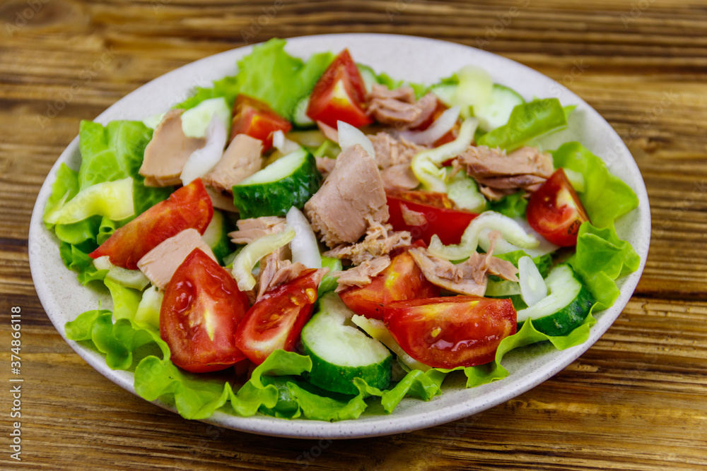 Tasty tuna salad with lettuce and fresh vegetables on wooden table