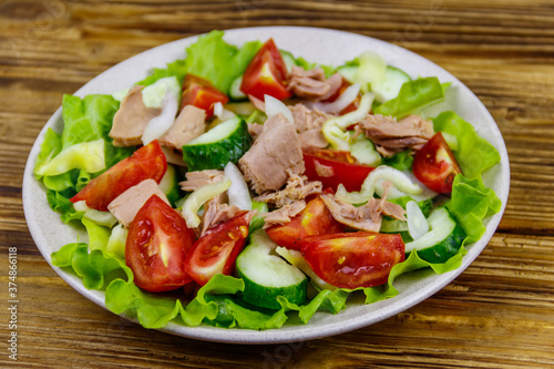 Tasty tuna salad with lettuce and fresh vegetables on wooden table