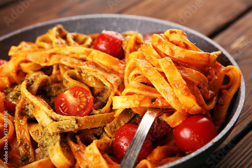 tagliatelle pasta with tomato sauce parmesan basil on rustic background