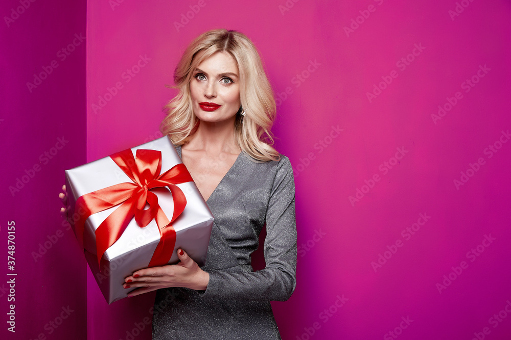 Beautiful sexy young blond girl with wavy hair bright evening make-up red lips long fluffy eyelashes hold gift box holiday New Year joy fun happy merry Christmas Eve party celebration. Beautiful sexy young blond girl with wavy hair bright evening make-up red lips long fluffy eyelashes hold gift box holiday New Year joy fun happy merry Christmas Eve party celebration.