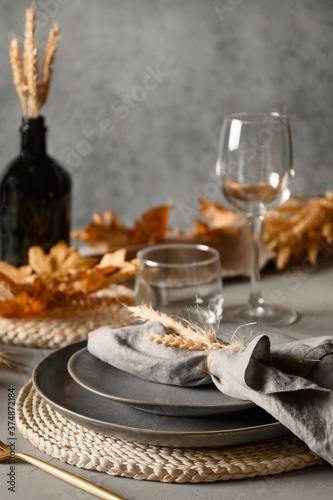 Autumn table setting with dry yellow oak leaves, fall decoration on grey table. Flat lay, top view. Thanksgiving day