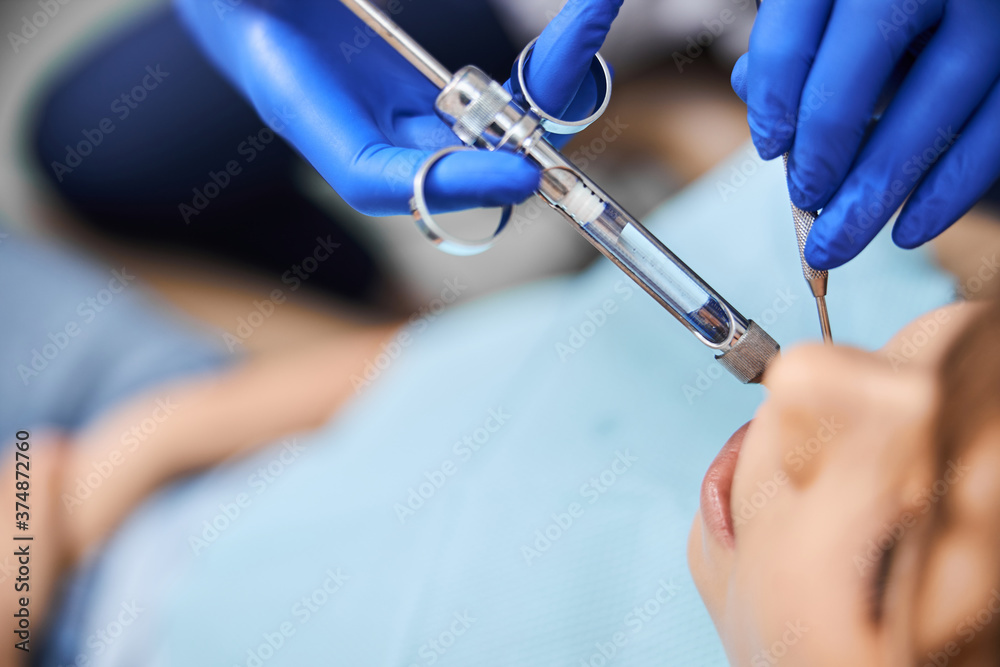 Dentist using a medical syringe for anesthesia Dentist using a medical syringe for anesthesia