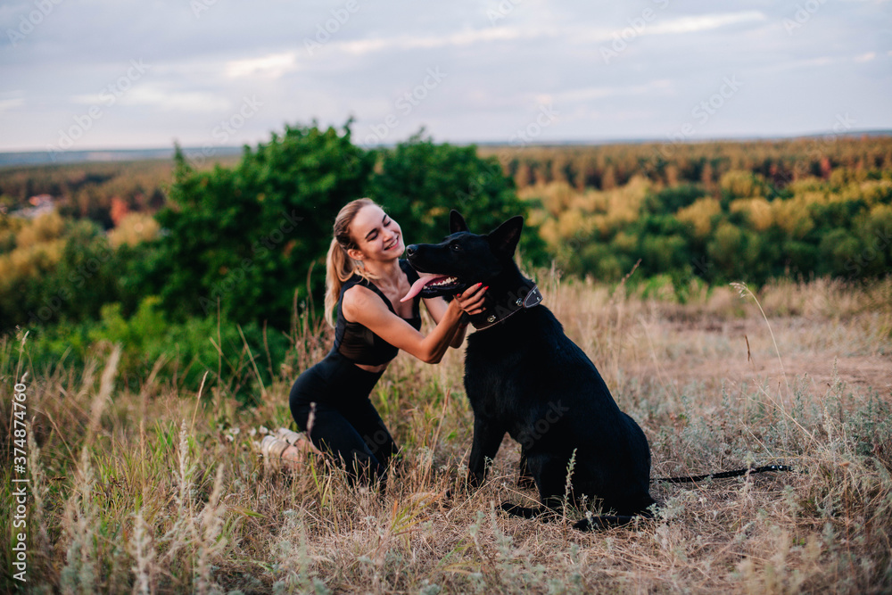 Young slender girl at sunset plays with a sheepdog Young slender girl at sunset plays with a sheepdog