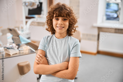 Smiley kid posing with arms crossed in doctor office