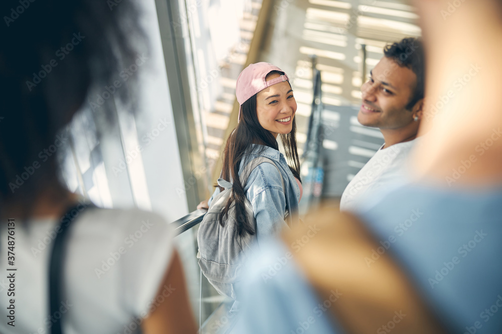 Smiling female and male on an moving staircase in the airport to catch a flight Smiling female and male on an moving staircase in the airport to catch a flight
