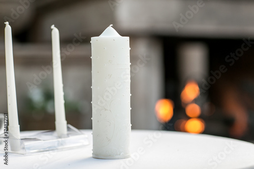 white candles for wedding ceremony in front of fireplace