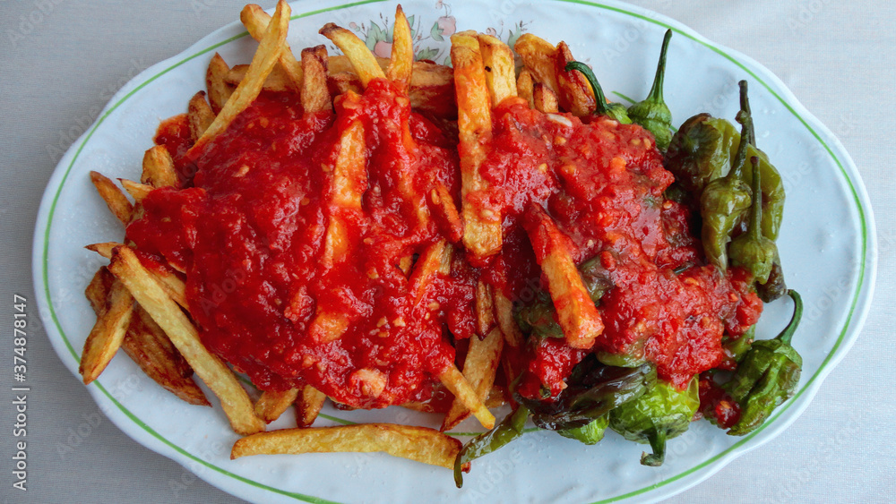 french fries covered with hot organic tomato sauce closeup in the white plate french fries covered with hot organic tomato sauce closeup in the white plate