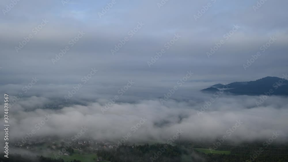 Time lapse low inversion clouds moving away on a large basin flatland. Farming fields and village covered with fog in Slovenia. Elevated aerial static view Time lapse low inversion clouds moving away on a large basin flatland. Farming fields and village covered with fog in Slovenia. Elevated aerial static view