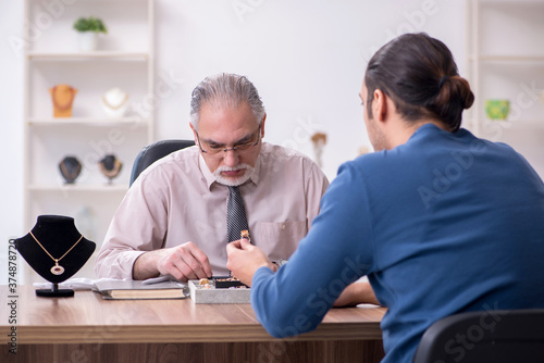 Young man visiting old male jeweler