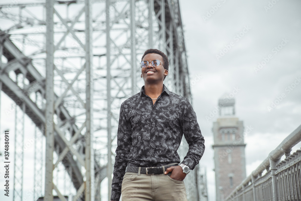 Young smiling attractive black man walking on the bridge in the city.