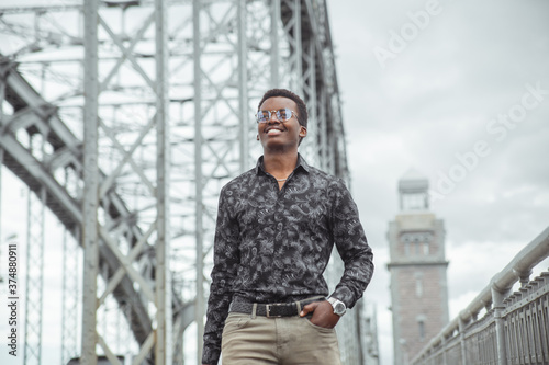 Young smiling attractive black man walking on the bridge in the city.