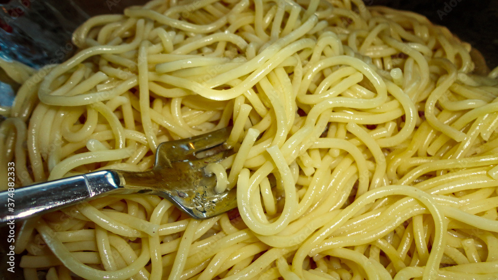 Large bowl with freshly cooked pasta and metal fork closeup