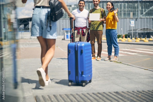 Woman with blue suitcase going to her tourist group
