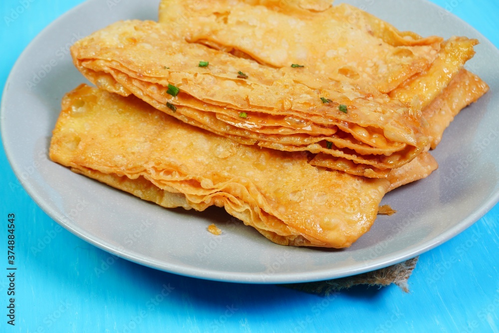 Crispy flour roti topped with sugar and chopped scallions