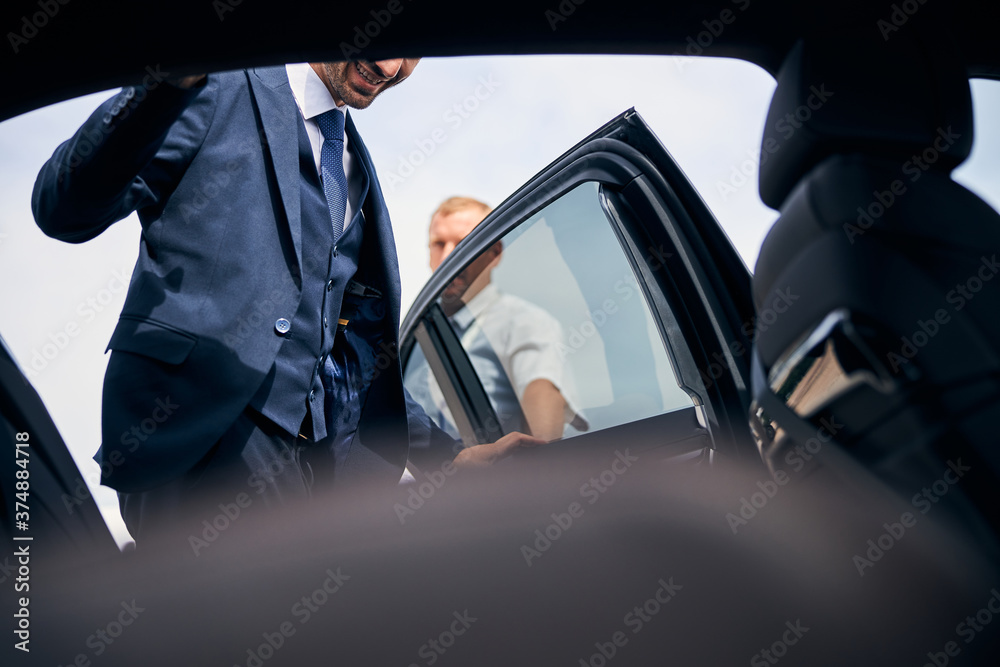 Cheerful businessman getting into a backseat of a car Cheerful businessman getting into a backseat of a car