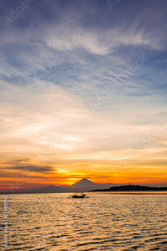 Sunset over a volcano and the ocean with a small traditional boat silhouette