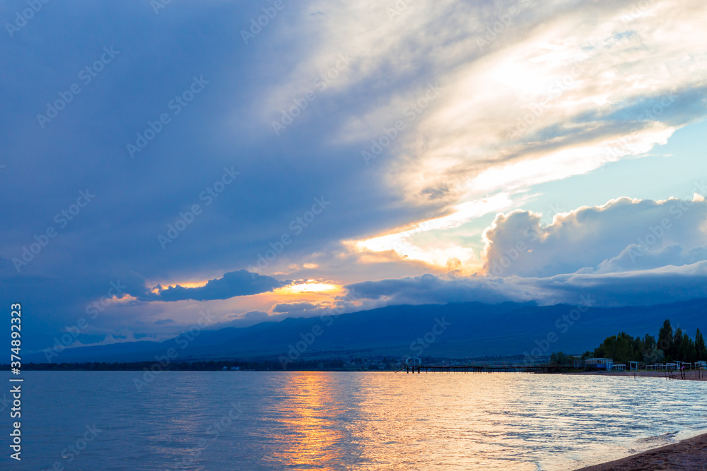 Beautiful sunset by the lake. Bright clouds are reflected in the water. Kyrgyzstan. Beautiful sunset by the lake. Bright clouds are reflected in the water. Kyrgyzstan.