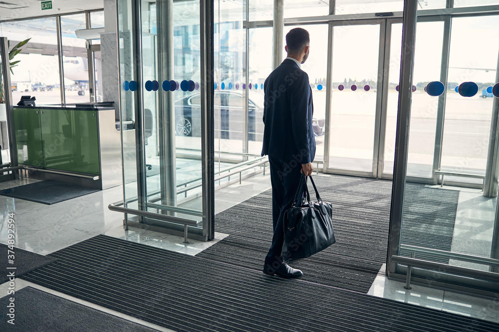 Fototapeta premium Young man leaving the airport with his luggage